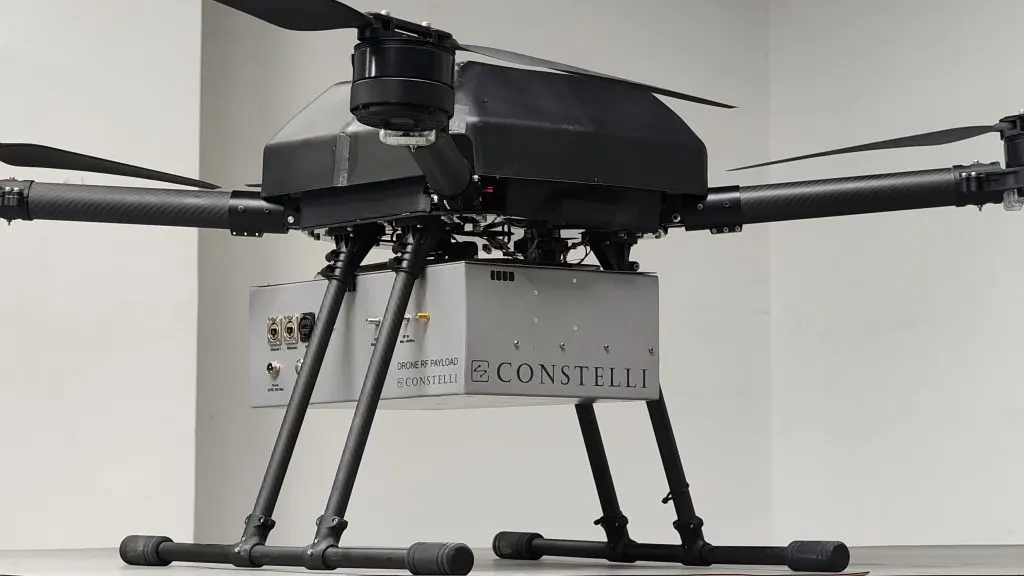 A multirotor drone carrying Constelli's branded Drone RF Payload unit beneath the airframe